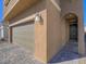 A close-up view of the two-car garage and arched entryway with dark brown door at 10279 Fragrant Apple Ct, Las Vegas, NV 89141