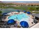 Aerial view of the community pool with blue umbrellas and surrounding landscape at 1407 Wheelwright Ct, Mesquite, NV 89034