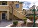 Tan two-story condo featuring well-kept landscaping and a covered staircase for access to the upper units at 1560 Jamielinn Ln # 101, Las Vegas, NV 89110