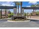 Elegant neighborhood entrance featuring stone pillars, lush landscaping, and mature palm trees at 2833 Athena Hill Ct, Henderson, NV 89052