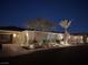 Night view of a home featuring a brick driveway, desert landscaping, and warm exterior lighting at 3120 Greenscape Ln, Las Vegas, NV 89138