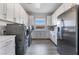 Spacious laundry room with washer, dryer, ample cabinetry, countertops, stainless steel refrigerator and wood tile flooring at 3120 Greenscape Ln, Las Vegas, NV 89138