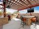 Full view of a fully equipped outdoor kitchen featuring a barbecue, bar seating, and shaded pergola at 5340 N Campbell Rd, Las Vegas, NV 89149