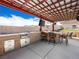 Well-equipped outdoor kitchen with a sink, BBQ, fridge, granite countertops and bar seating under a covered patio at 5340 N Campbell Rd, Las Vegas, NV 89149
