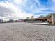 Wide shot of a large gravel lot with a home and various structures in the background on a clear day at 5340 N Campbell Rd, Las Vegas, NV 89149