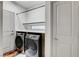 Laundry area showcasing modern washer and dryer units with overhead shelving and adjacent door at 6618 Tangled Vines Ave, Las Vegas, NV 89139