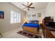 Cozy bedroom featuring a comfortable bed, ceiling fan, and view to shuttered window at 671 W Hickory St, Pahrump, NV 89048