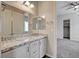 Bright bathroom featuring dual sinks, white cabinetry, and granite countertops, with a doorway leading to the bedroom at 7119 Falabella Ridge Ave, Las Vegas, NV 89131