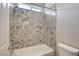 Bathroom showing a white tub and granite shower walls next to a toilet with a window for natural light at 7119 Falabella Ridge Ave, Las Vegas, NV 89131