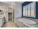 Bathroom featuring a soaking tub with granite surround, walk-in shower and shuttered window at 7119 Falabella Ridge Ave, Las Vegas, NV 89131