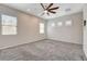 Expansive bedroom showcasing plush gray carpet, a ceiling fan, and windows with natural light at 7119 Falabella Ridge Ave, Las Vegas, NV 89131