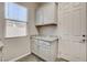 A laundry room featuring granite countertops, white cabinets, wood-look tile flooring, and a window for natural light at 7119 Falabella Ridge Ave, Las Vegas, NV 89131