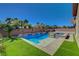Backyard pool with integrated waterfall and adjacent spa, surrounded by mature landscaping and artificial turf at 7119 Falabella Ridge Ave, Las Vegas, NV 89131