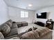 Comfortable living room featuring a plush sectional sofa, window blinds, and a wall-mounted TV, perfect for cozy evenings at 760 Crisp Morning Ct, North Las Vegas, NV 89086