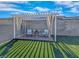 Cozy backyard with pergola, curtains, two chairs, table, and manicured synthetic grass at 10009 Locking Biner Ave, Las Vegas, NV 89166