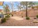 Landscaped backyard with desert-style gravel, trees, bushes, and retaining wall at 10041 Arbuckle Dr, Las Vegas, NV 89134