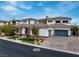 An elegant two-story home featuring a stone facade, well-manicured landscaping, and a three-car garage at 12 Olympia Chase Dr, Las Vegas, NV 89141
