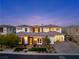 Beautiful home exterior with a well-manicured lawn, elegant lighting, and a three-car garage, offering curb appeal at 12 Olympia Chase Dr, Las Vegas, NV 89141