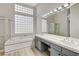 Bright bathroom with a soaking tub, shower, double vanity, and glass block window at 1700 Wandering Winds Way, Las Vegas, NV 89128