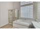 Bright bathroom featuring a soaking tub with unique glass block window and glass-enclosed shower at 1700 Wandering Winds Way, Las Vegas, NV 89128