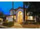 Charming stucco home with arched entryway, lush landscaping, and attached two-car garage at 1700 Wandering Winds Way, Las Vegas, NV 89128
