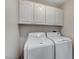 Practical laundry room with upper cabinets and modern, matching washer and dryer units at 1700 Wandering Winds Way, Las Vegas, NV 89128