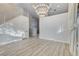 Spacious living room with modern light fixture, a staircase with white railings, and light wood floors at 1700 Wandering Winds Way, Las Vegas, NV 89128