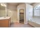 Bathroom featuring a walk-in shower, tub, single vanity and doorway to a walk-in closet at 2020 Sinfonia Ave, Henderson, NV 89052
