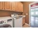 Bright laundry room features a modern washer and dryer, cabinets, and utility sink at 2020 Sinfonia Ave, Henderson, NV 89052