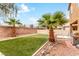 Beautifully landscaped backyard with artificial turf, rockscape, palm trees and a grill on the patio at 2199 Timescape Ct, Las Vegas, NV 89123