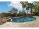 Inviting backyard pool with a rock waterfall feature and stone coping, set amongst tropical landscaping and palm trees at 2323 Carinth Way, Henderson, NV 89074