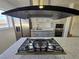 Island cooktop and stainless steel hood vent with marble countertop and stainless steel appliances at 4754 Marnell Dr, Las Vegas, NV 89121