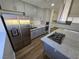 Kitchen island with cooktop, stainless steel refrigerator, granite countertops, and grey cabinets at 4754 Marnell Dr, Las Vegas, NV 89121