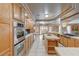 Spacious kitchen with oak cabinets, tile countertops, stainless appliances, and a center island at 6491 Bright Nimbus Ave, Las Vegas, NV 89139