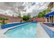 Backyard pool with blue tile trim, surrounded by a brick privacy wall and complemented by tropical landscaping for relaxation at 6491 Bright Nimbus Ave, Las Vegas, NV 89139