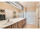 Bathroom featuring double sinks, a large mirror with vanity lighting, and a glass-enclosed shower for convenience at 7567 Wingspread St, North Las Vegas, NV 89084