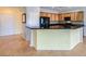 An open kitchen featuring wood cabinets, granite countertops, a breakfast bar, and neutral paint at 7567 Wingspread St, North Las Vegas, NV 89084