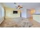 Comfortable living area featuring a ceiling fan, TV on the wall, and carpet, with adjacent access to the kitchen at 7567 Wingspread St, North Las Vegas, NV 89084