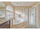 Bright bathroom showcasing a corner tub, glass-enclosed shower, and tiled walls at 7581 Slipstream St, Las Vegas, NV 89139