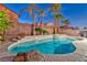 Sparkling pool surrounded by lush landscaping, mature palm trees, and rock features at 7581 Slipstream St, Las Vegas, NV 89139