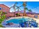 Backyard oasis featuring a sparkling pool, spa, palm trees, and outdoor seating at 7581 Slipstream St, Las Vegas, NV 89139