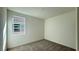 A minimalist bedroom with neutral carpet, walls, and a window bringing in light at 9067 Mapledale Ranch Ct, Las Vegas, NV 89139