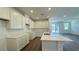 A modern kitchen with white cabinetry, an island, and sliding door to backyard at 9067 Mapledale Ranch Ct, Las Vegas, NV 89139