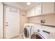 Bright laundry room with washer, dryer, white cabinets, and door to the outside at 1209 Shifting Sands Dr, Las Vegas, NV 89108