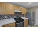 Close-up of kitchen featuring stainless steel stove and backsplash and light wood cabinetry at 141 Fox Lake Ave, Las Vegas, NV 89148