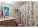 Bright bathroom featuring wood vanity, a toilet with a red plush cover, and a floral shower curtain at 1892 Maricopa Dr, Laughlin, NV 89029