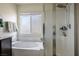 Bright bathroom featuring a soaking tub, glass-enclosed shower, and frosted window for privacy at 340 Largo Vista Ct, North Las Vegas, NV 89084