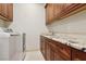 Functional laundry room with wooden cabinets, granite countertop, and modern washer and dryer at 3863 Glasgow Green Dr, Las Vegas, NV 89141