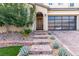 Inviting front entrance with decorative stone steps, lush greenery, and a modern glass-paneled garage door at 3929 Reyes Ave, Las Vegas, NV 89141