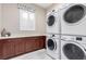 Laundry room featuring a window, cabinets, counter, and stacked washer and dryer at 3929 Reyes Ave, Las Vegas, NV 89141